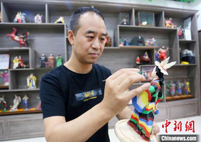 圖為安秋平正在創(chuàng)作代表隴南文縣民俗的《白馬人》作品。　高展 攝