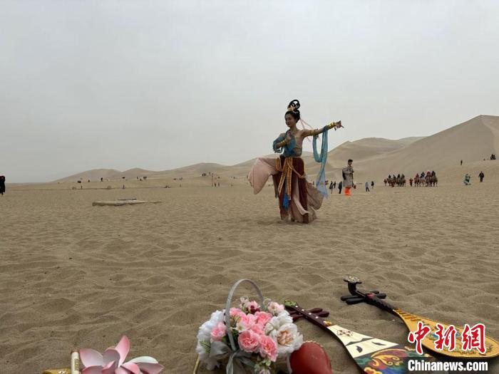 圖為2023年4月底，敦煌大漠“逐舞者”奧楠在鳴沙山月牙泉景區(qū)視頻直播敦煌舞?！●T志軍 攝