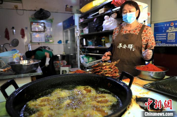 圖為平安驛·河湟民俗文化體驗(yàn)地內(nèi)的商戶炸干板魚?！⊙Φ?攝